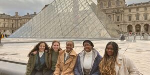 A group of glo explore students sitting in front of the louvre