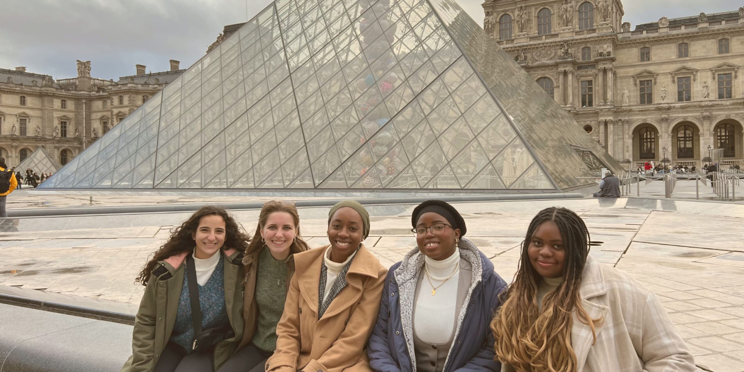 A group of glo explore students sitting in front of the louvre