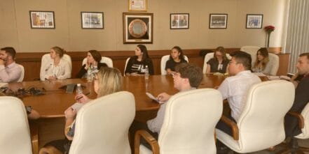 GLO srudents sitting around the table listening to a business speaker